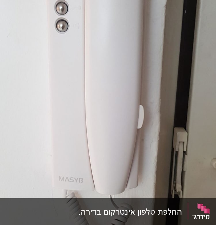 אינטרקום לבן עם שפופרת וכפתורים על הקיר